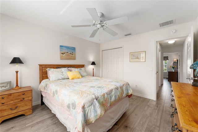 bedroom with a closet, light wood finished floors, baseboards, and ceiling fan