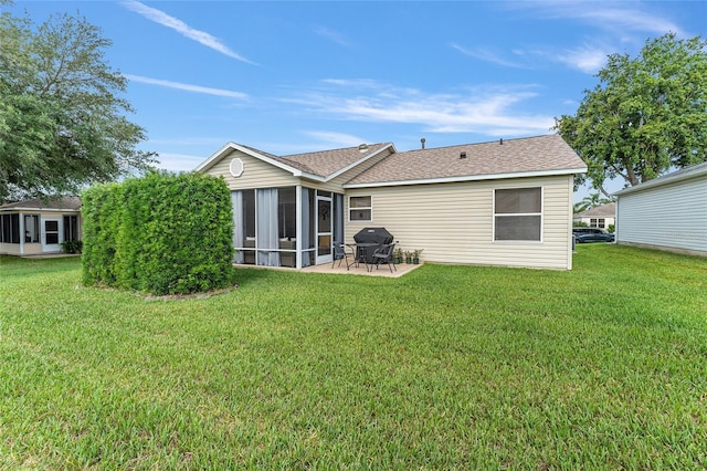back of property with a sunroom, a lawn, a patio area, and roof with shingles