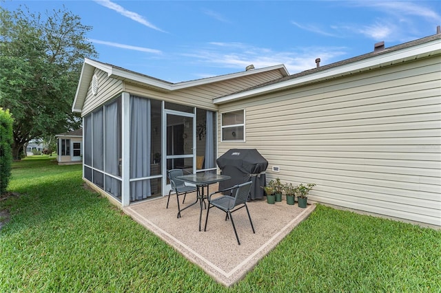 back of house featuring a sunroom and a lawn