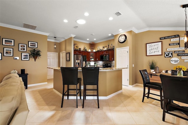 1053 Alcove Loop, The Villages, FL 32162 - kitchen with stainless steel appliances, open floor plan, a breakfast bar area, crown molding, and tasteful backsplash