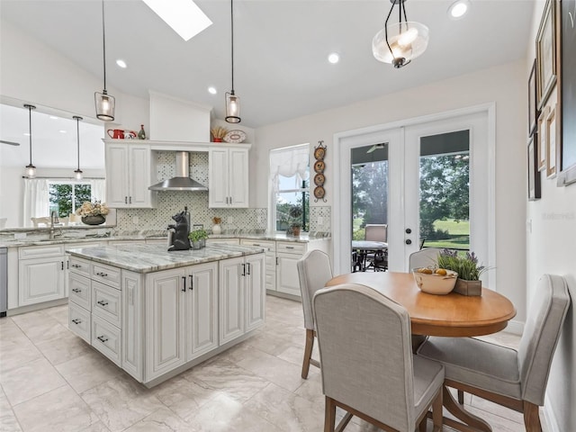 563 Dowling Cir, Lady Lake, FL 32159 - kitchen featuring wall chimney range hood, white cabinetry, a skylight, decorative light fixtures, and lofted ceiling