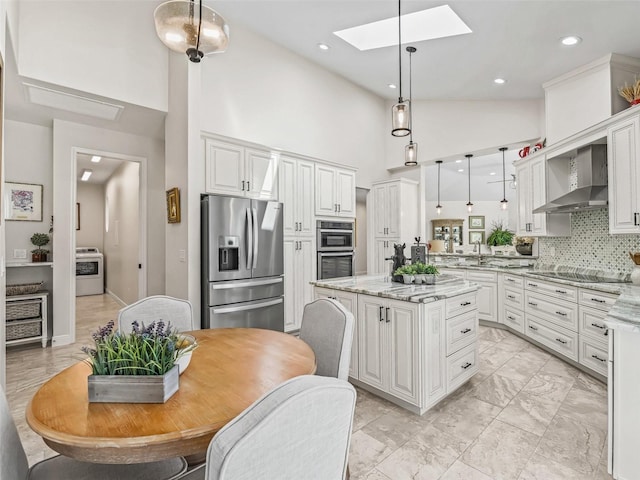 563 Dowling Cir, Lady Lake, FL 32159 - kitchen with appliances with stainless steel finishes, washer / clothes dryer, wall chimney exhaust hood, a skylight, and high vaulted ceiling