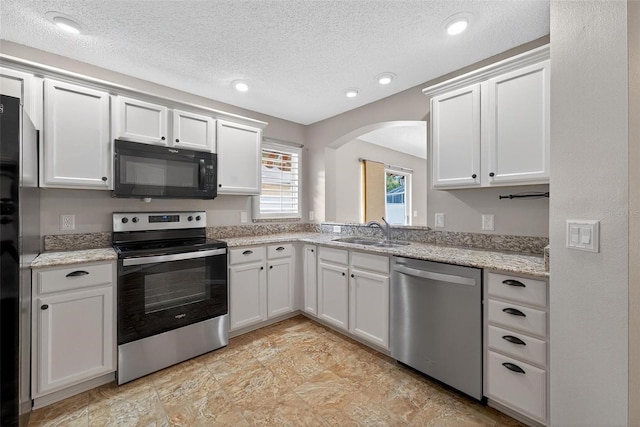 2744 Gresham Ave, The Villages, FL 32162 - kitchen featuring appliances with stainless steel finishes, a sink, arched walkways, a textured ceiling, and white cabinetry