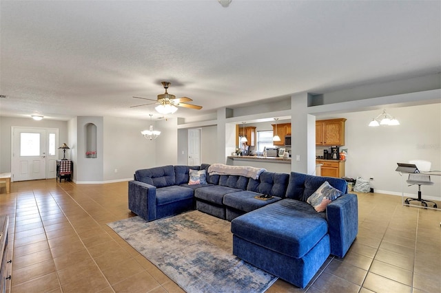 living room featuring a chandelier, light tile patterned floors, a ceiling fan, baseboards, and a textured ceiling