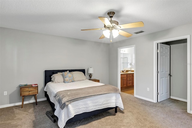 bedroom with light colored carpet, baseboards, a ceiling fan, and ensuite bath