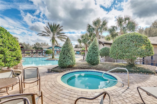 community pool featuring a hot tub and a patio area