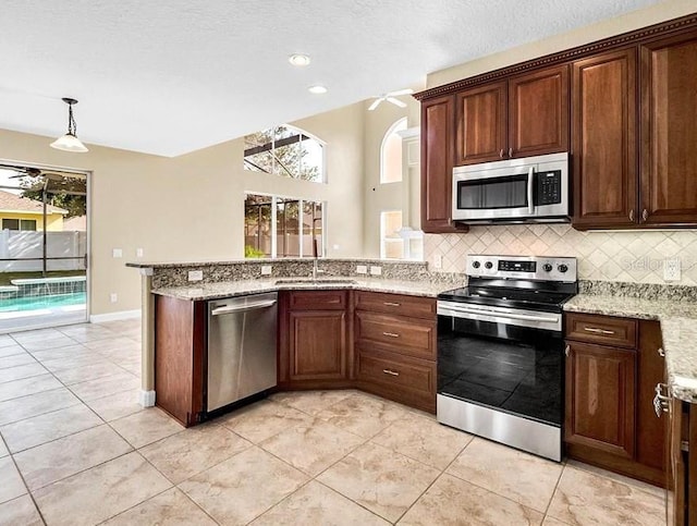 108 Whispering Pines Way, Davenport, FL 33837 - kitchen with appliances with stainless steel finishes, a sink, a peninsula, decorative backsplash, and light stone countertops