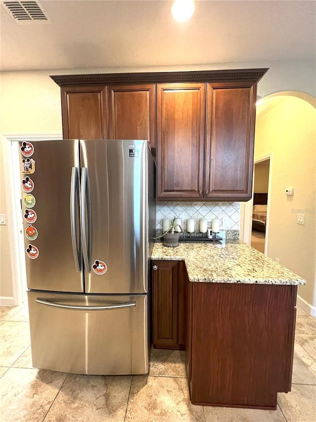 108 Whispering Pines Way, Davenport, FL 33837 - kitchen featuring freestanding refrigerator, arched walkways, tasteful backsplash, light stone counters, and baseboards
