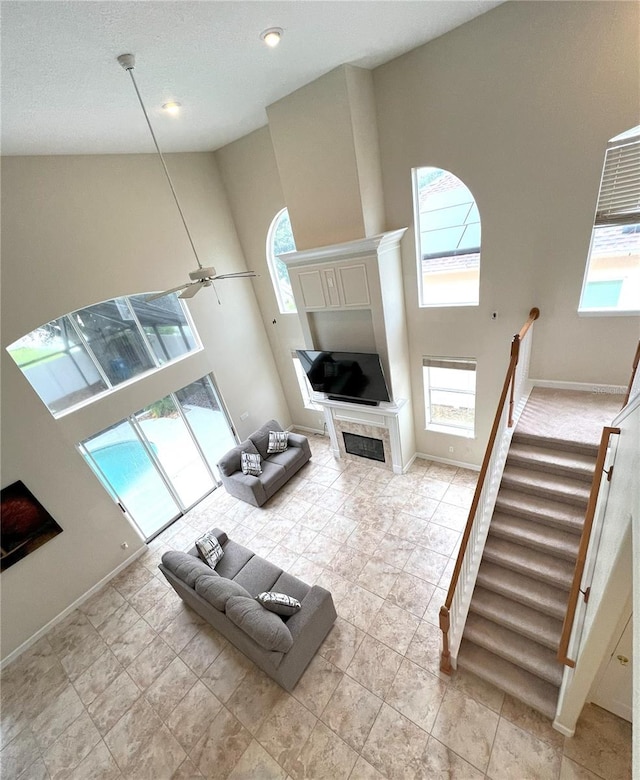 108 Whispering Pines Way, Davenport, FL 33837 - living room featuring healthy amount of natural light, a high ceiling, stairway, baseboards, and a tiled fireplace