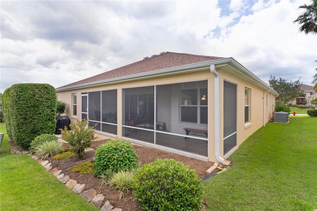 627 Leeds Pl, The Villages, FL 32162 - back of house with a sunroom, stucco siding, a lawn, central AC, and roof with shingles
