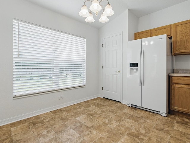 8601 SE 133rd St, Summerfield, FL 34491 - kitchen with white fridge with ice dispenser, a chandelier, baseboards, and brown cabinets