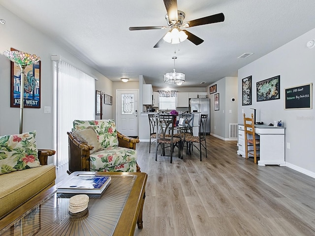 1722 Moreno Pl, The Villages, FL 32159 - living area featuring a ceiling fan, light wood-type flooring, baseboards, a chandelier, and a textured ceiling
