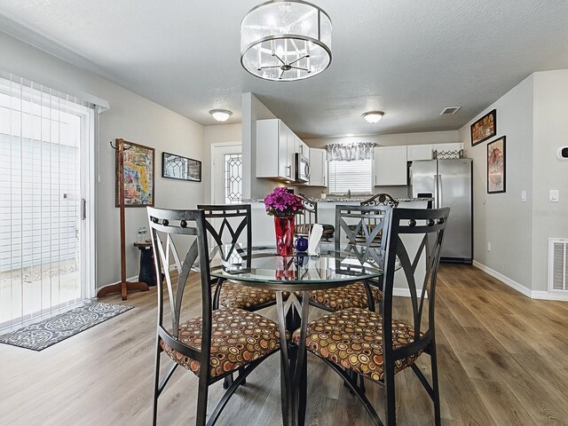 1722 Moreno Pl, The Villages, FL 32159 - dining area with light wood-style floors, baseboards, a chandelier, and a textured ceiling
