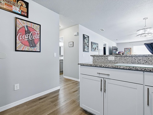 1722 Moreno Pl, The Villages, FL 32159 - bar with light wood finished floors, baseboards, a chandelier, pendant lighting, and a textured ceiling