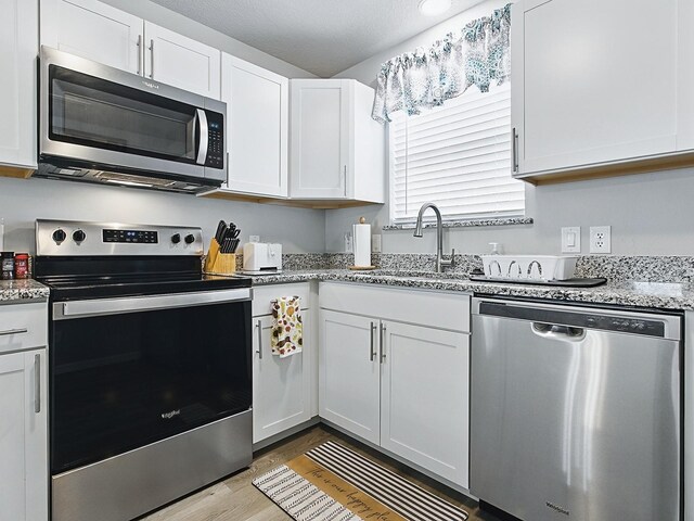 1722 Moreno Pl, The Villages, FL 32159 - kitchen featuring stainless steel appliances, a sink, wood finished floors, and white cabinetry