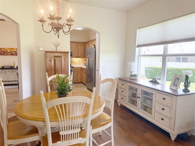 dining room featuring arched walkways, light wood-style flooring, and a chandelier