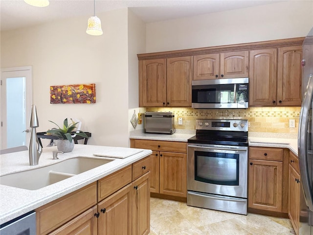 kitchen with appliances with stainless steel finishes, a sink, light countertops, and decorative backsplash