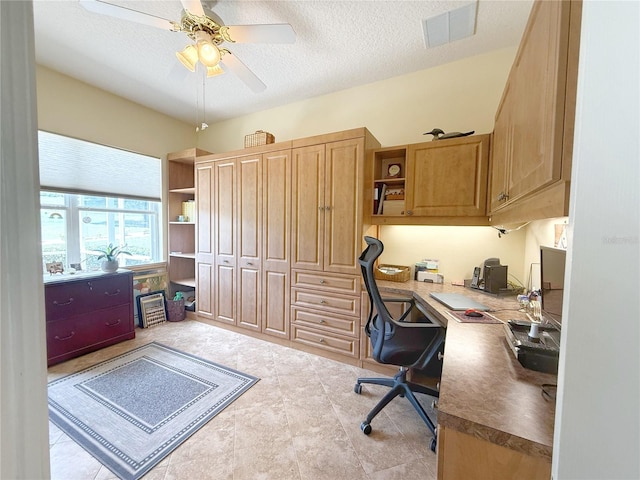 office with a ceiling fan, a textured ceiling, and built in study area