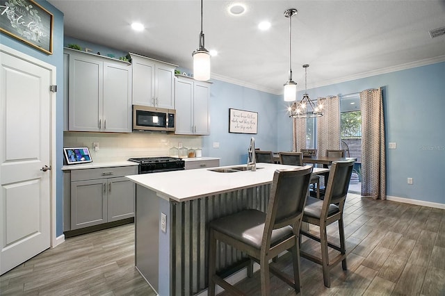 1155 Dora Parc Ln, Mount Dora, FL 32757 - kitchen with stainless steel microwave, gray cabinetry, light wood-style flooring, decorative backsplash, and ornamental molding
