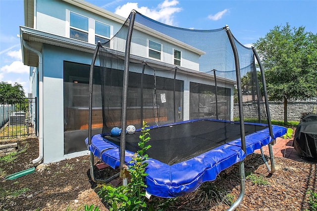 1155 Dora Parc Ln, Mount Dora, FL 32757 - rear view of property with a trampoline, stucco siding, and a sunroom