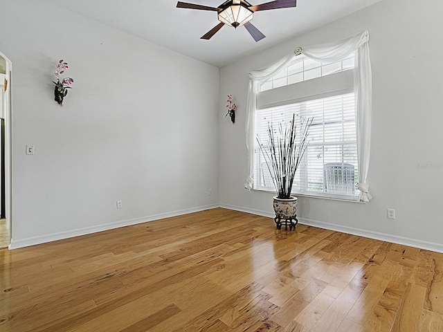 spare room featuring healthy amount of natural light, ceiling fan, wood finished floors, and baseboards