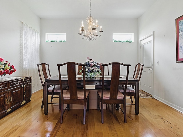 dining room featuring a chandelier, healthy amount of natural light, and light wood-type flooring