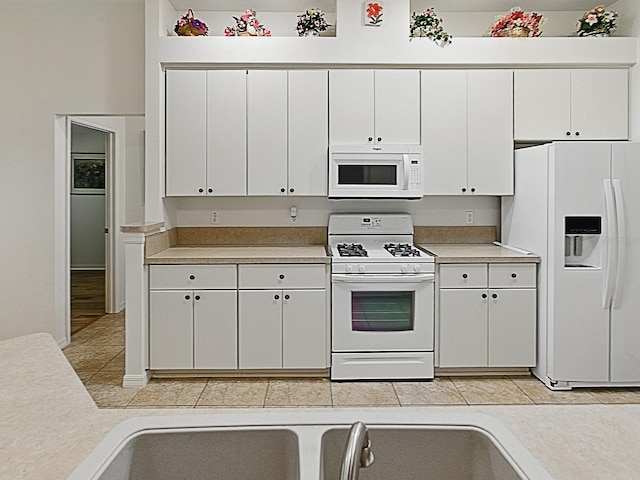kitchen with white appliances, light countertops, and white cabinetry