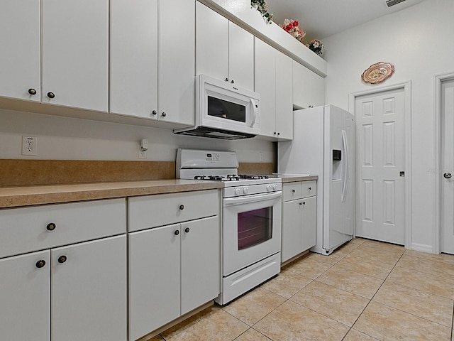 kitchen featuring white appliances, light countertops, light tile patterned flooring, and white cabinets