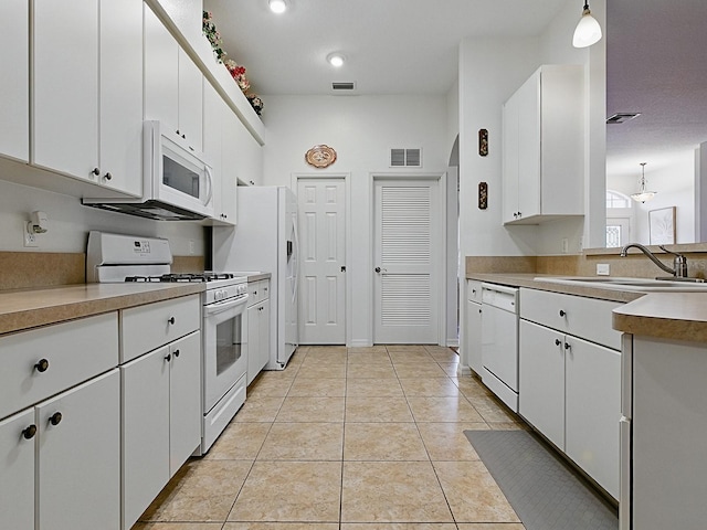 kitchen with white appliances, a sink, white cabinets, light tile patterned flooring, and light countertops
