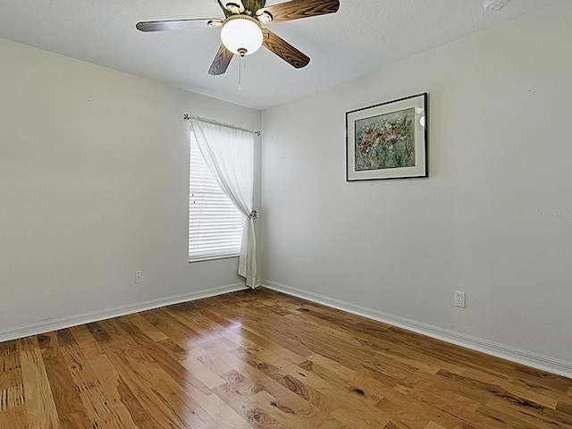 unfurnished room with wood finished floors, baseboards, and a ceiling fan