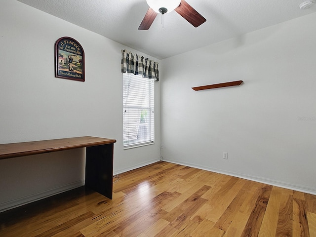 spare room with a smoke detector, wood finished floors, ceiling fan, and baseboards