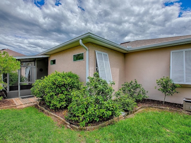 view of side of home with stucco siding and a lawn