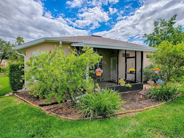 view of front of property featuring stucco siding, a front yard, and a sunroom
