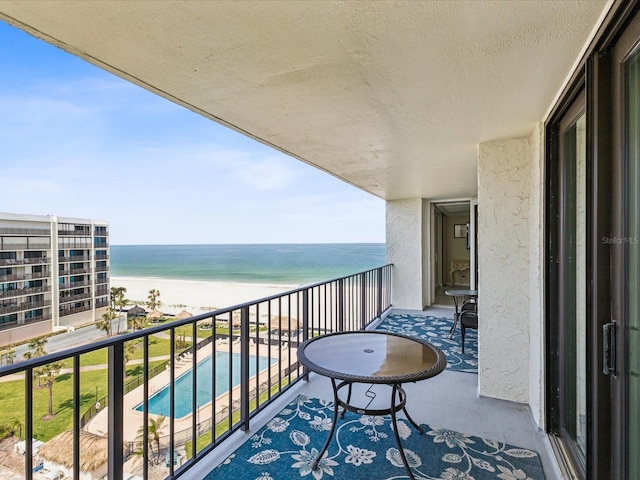 balcony with view of water and beach and view of pool
