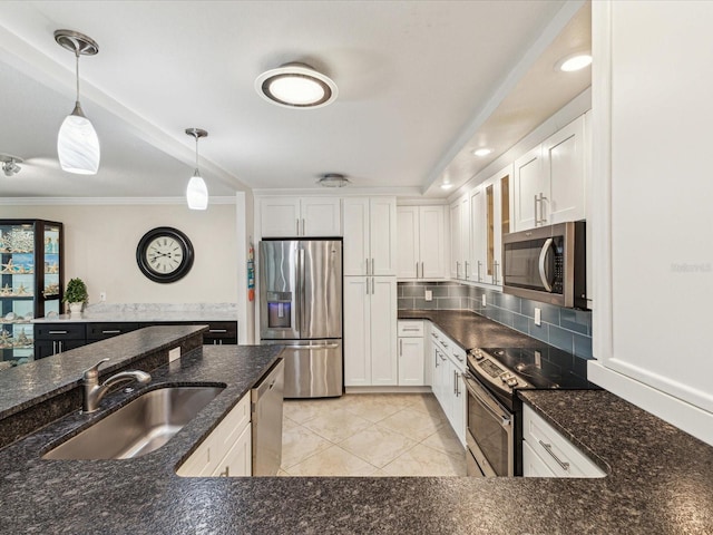 kitchen with appliances with stainless steel finishes, a sink, hanging light fixtures, ornamental molding, and white cabinets