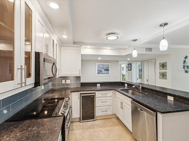 kitchen with stainless steel appliances, a sink, white cabinets, dark stone countertops, and recessed lighting