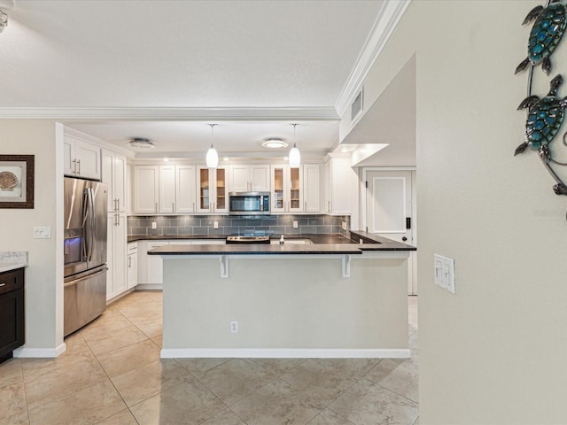 kitchen featuring stainless steel appliances, ornamental molding, decorative backsplash, dark countertops, and white cabinets