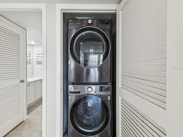 laundry room with estacked washer and dryer and light marble finish floors