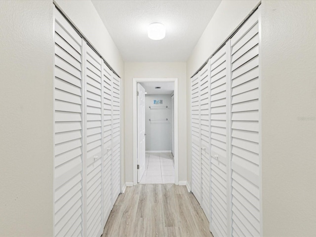 hallway featuring wood finished floors, a textured ceiling, and baseboards