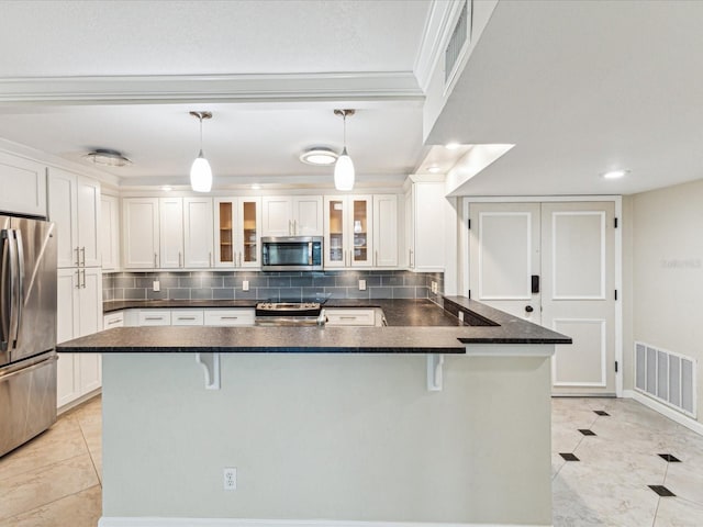 kitchen with appliances with stainless steel finishes, white cabinetry, a kitchen breakfast bar, tasteful backsplash, and recessed lighting