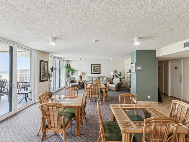 dining area featuring carpet, a textured ceiling, and a wall of windows