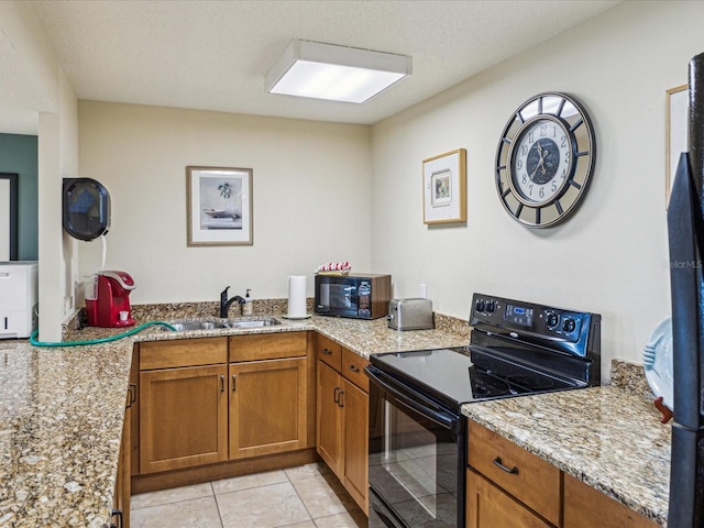 kitchen with black appliances, brown cabinets, light stone counters, light tile patterned floors, and a sink