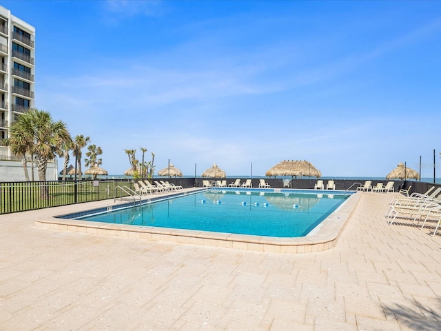 community pool with a patio and fence