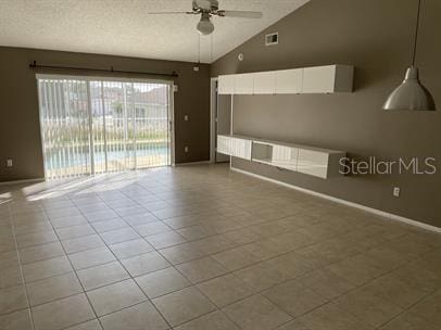 3041 Bloomsbury Dr, Kissimmee, FL 34747 - tiled empty room with a ceiling fan, vaulted ceiling, a textured ceiling, and baseboards