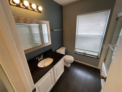 3041 Bloomsbury Dr, Kissimmee, FL 34747 - bathroom with a shower with shower door, toilet, vanity, baseboards, and wood finished floors