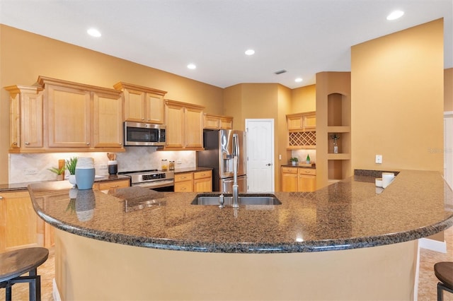 1123 Barnacle Ter, The Villages, FL 32162 - kitchen featuring stainless steel appliances, a peninsula, light brown cabinets, decorative backsplash, and dark stone countertops