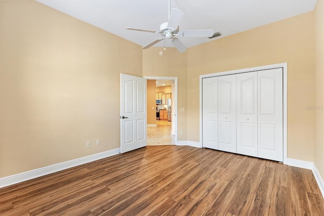 1123 Barnacle Ter, The Villages, FL 32162 - unfurnished bedroom featuring wood finished floors, baseboards, a closet, a ceiling fan, and a high ceiling