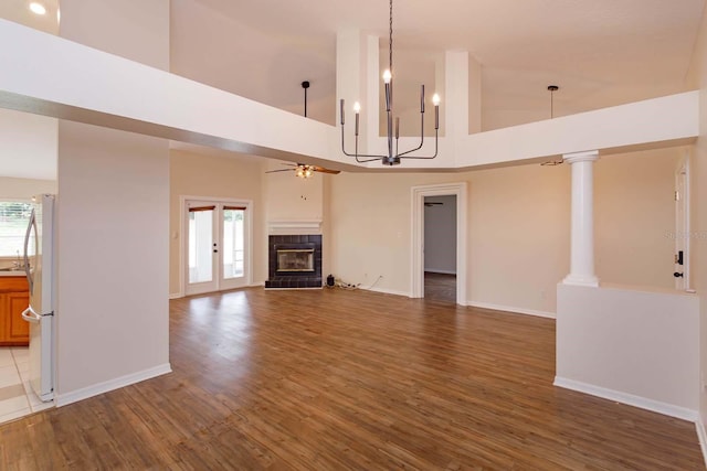 11442 Beggs Ct, Clermont, FL 34711 - unfurnished living room with a towering ceiling, a ceiling fan, a tiled fireplace, wood finished floors, and baseboards