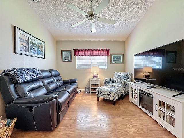 living room featuring a textured ceiling, light wood finished floors, and ceiling fan