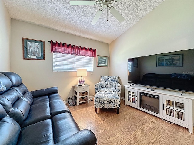 living area with ceiling fan, a textured ceiling, lofted ceiling, and wood finished floors